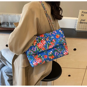 Detail of blue canvas crossbody bag with phoenix peony print and metal chain strap