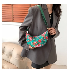 Detail of green floral crescent shoulder bag with red roses and wide canvas strap