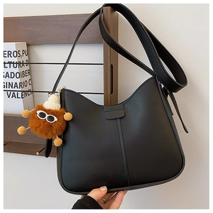 Minimalist black PU leather crescent shoulder bag with a cute brown plush monster charm