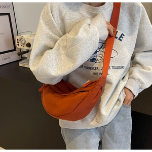 Dettaglio della borsa a tracolla arancione a mezzaluna alla moda con ampia tracolla regolabile