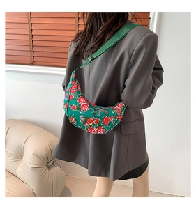 Detailed view of green crescent nylon shoulder bag with red floral pattern on model