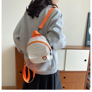 Détail du mini sac à dos en toile blanc avec bretelles orange dans un décor décontracté