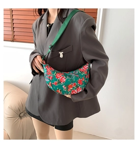 Detail view of a green floral crescent bag worn over a gray oversized blazer