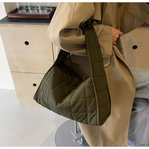 Close-up of quilted dark green tote bag featuring rhombus pattern and wide shoulder strap