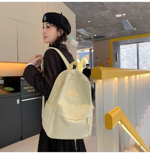 Vue latérale d'un sac à dos en nylon jaune crème porté par un mannequin en public