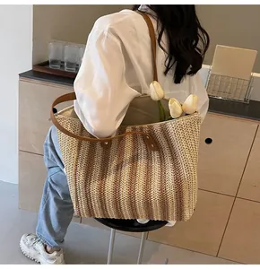 Detail of hand-woven straw tote bag with brown leather straps and vertical stripes
