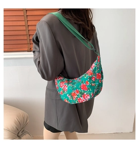 Retro green floral canvas crossbody bag with red rose pattern worn by a model over a suit