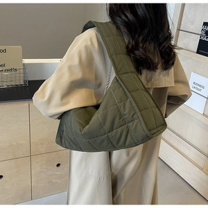 Detail of dark green quilted shoulder bag with padded rhombic stitching on canvas fabric
