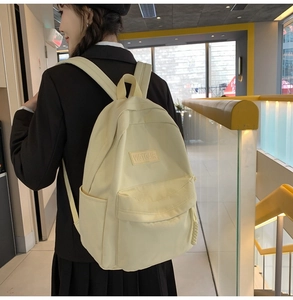 Détail d'un sac à dos en nylon jaune pastel montrant la poche latérale et le logo