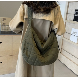 Detail view showing a large olive green quilted hobo bag with a soft puffer texture