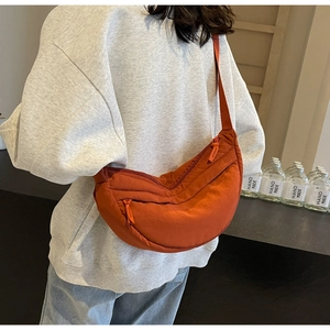 Dettaglio della borsa a tracolla in nylon arancione con trama trapuntata e doppia zip