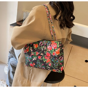 Detail of floral canvas crossbody bag featuring colorful peacock and flower prints