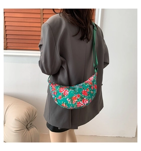Close-up of floral nylon crescent bag worn over a grey blazer in a modern setting