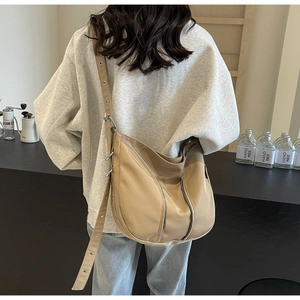 Detail of khaki nylon tote bag featuring multiple metal zippers and adjustable wide strap