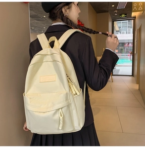 Vue détaillée du sac à dos en nylon beige avec poche latérale et tirettes de fermeture