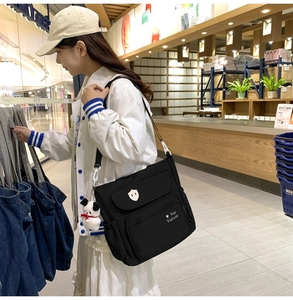 Dettaglio della borsa in nylon nero con un ciondolo di peluche a forma di cucciolo