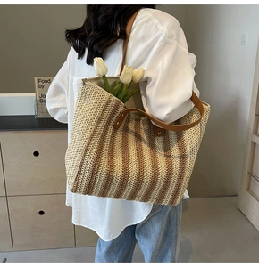 Détail macro du sac cabas en paille rayé avec anses en cuir marron et fermeture éclair