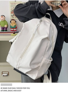 Detail view of a white nylon backpack featuring side drawstring pockets and durable woven straps