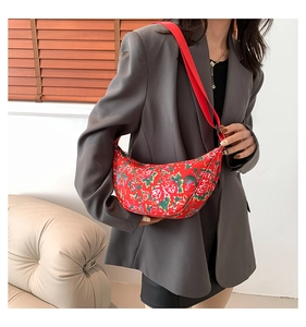 Detail of red crescent nylon shoulder bag featuring traditional floral pattern print