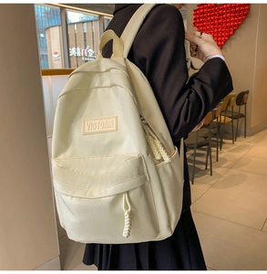 Vue latérale d'un sac à dos en nylon beige avec tirettes de fermeture en corde tressée