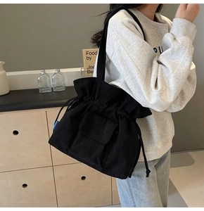 Nahaufnahme der schwarzen Cord-Beuteltasche mit Kordelzug und Vordertasche am Modell
