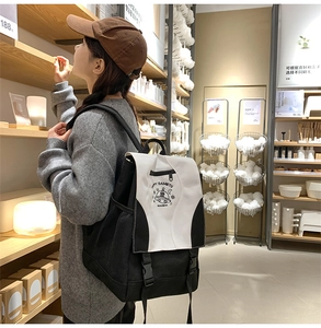Close-up of black and white canvas backpack featuring cartoon planet print and side mesh pocket