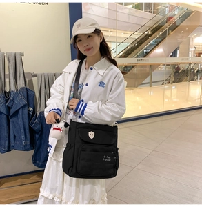 Borsa a tracolla alla moda in nylon nero con design multitasche indossata da modella