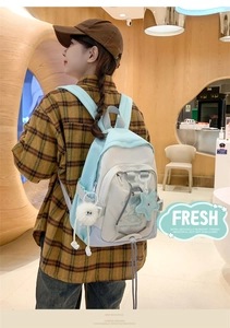 Detail of blue and white nylon backpack with cute spaceship print and plush charms