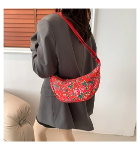 Rear view of a model wearing a red floral nylon crescent shoulder bag over a grey blazer