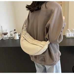 Borsa a tracolla a mezzaluna beige in tela con ampia cinghia regolabile indossata dal modello