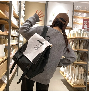 Detail of black and white canvas backpack featuring a bell graphic and side mesh pocket