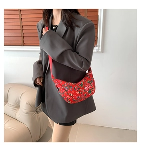 Detail of red floral crescent crossbody bag with nylon fabric on a grey blazer
