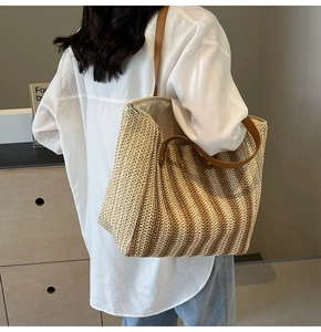 Détail du sac cabas en paille à rayures avec anses en cuir marron et fermeture éclair