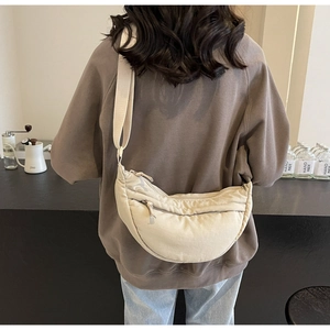 Vista dettagliata di una borsa a mezzaluna in nylon beige indossata da una modella al caffè