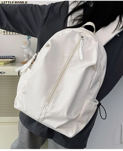 Detail of white nylon backpack featuring a unique vertical zipper and side pocket