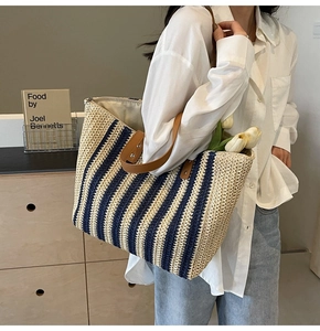 Detail of striped woven straw tote bag with brown leather straps and large capacity