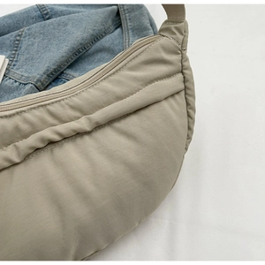 Detailed close-up of beige nylon crossbody bag with textured pleats and zipper