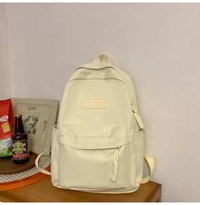 Détail du sac à dos en nylon crème avec logo VICTOAIR sur surface en bois