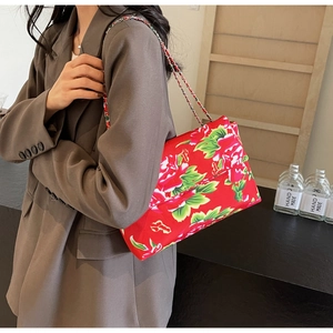 Detail view of the red floral canvas crossbody bag with silver chain strap on model