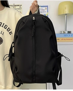Detail of minimalist black nylon backpack with unique vertical zipper and woven puller