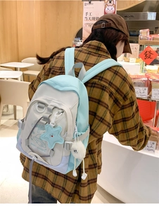 Detail of light blue and beige nylon backpack with cartoon UFO print and plush star charm