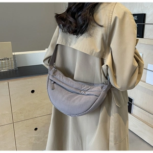 Detail view of the crescent nylon crossbody bag in taupe with long strap and sleek zipper