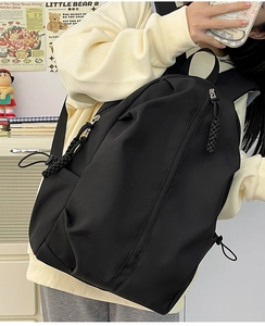 Side view of a large black nylon backpack on model with woven rope zipper detail