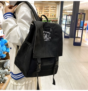 Detail of black nylon backpack featuring cartoon UFO embroidery and side mesh pocket