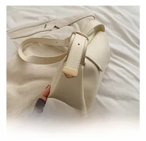 Detail shot of a beige PU leather handbag featuring polished gold-tone metal hardware