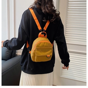 Détail du mini sac à dos en toile jaune avec sangles orange et boucle en anneau en D