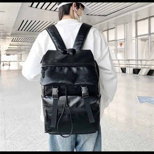 Detail showing the glossy PU leather texture and double buckle closure of the black backpack