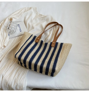 Détail du sac cabas en paille avec poignées en cuir marron et rayures bleues