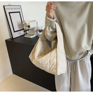 Detail view of beige quilted tote bag with square pattern showing nylon texture and shape