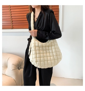 Detail view of oversized quilted cloud bag in beige nylon fabric shown on shoulder